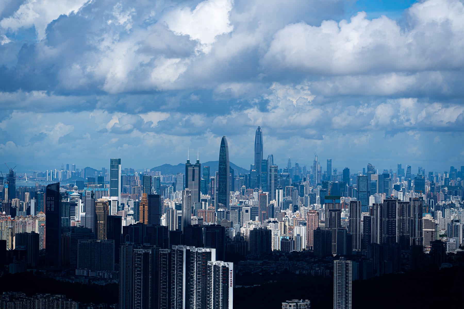 高空俯瞰深圳建筑群，明亮积云覆盖城市上空
