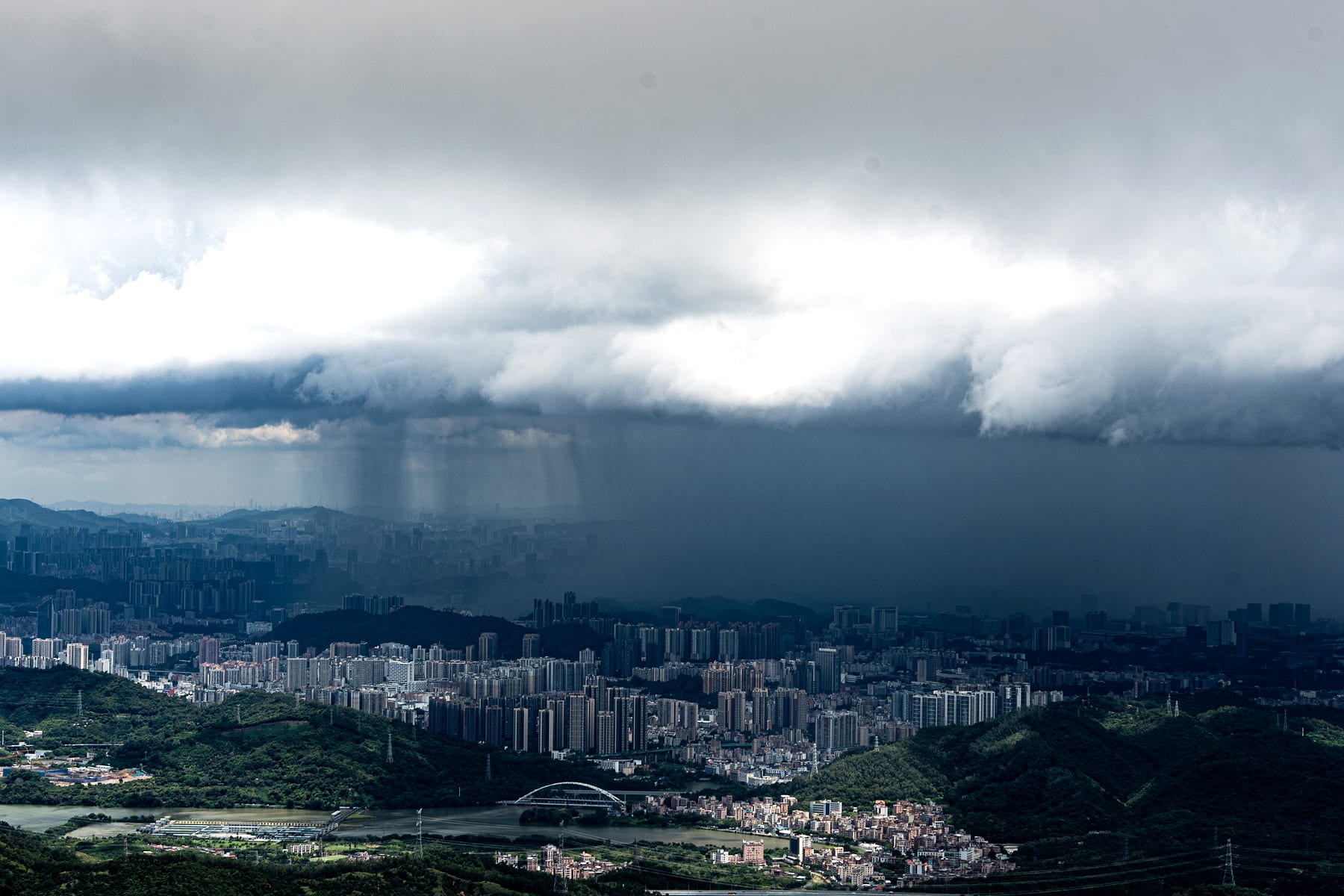 厚重雨云压过城市,远处雨幕落在建筑群上